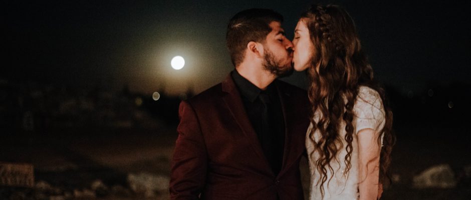 A couple is kissing when it's full moonlight