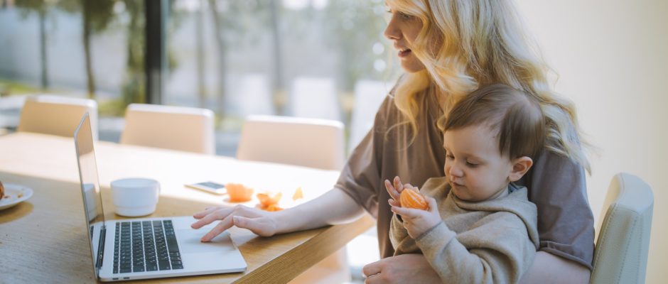 single mom carrying her baby and using laptop for online dating