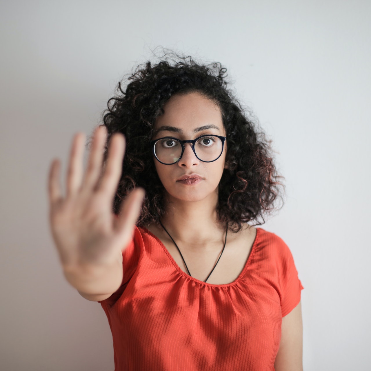 a woman in red holding out her hand in stop gesture