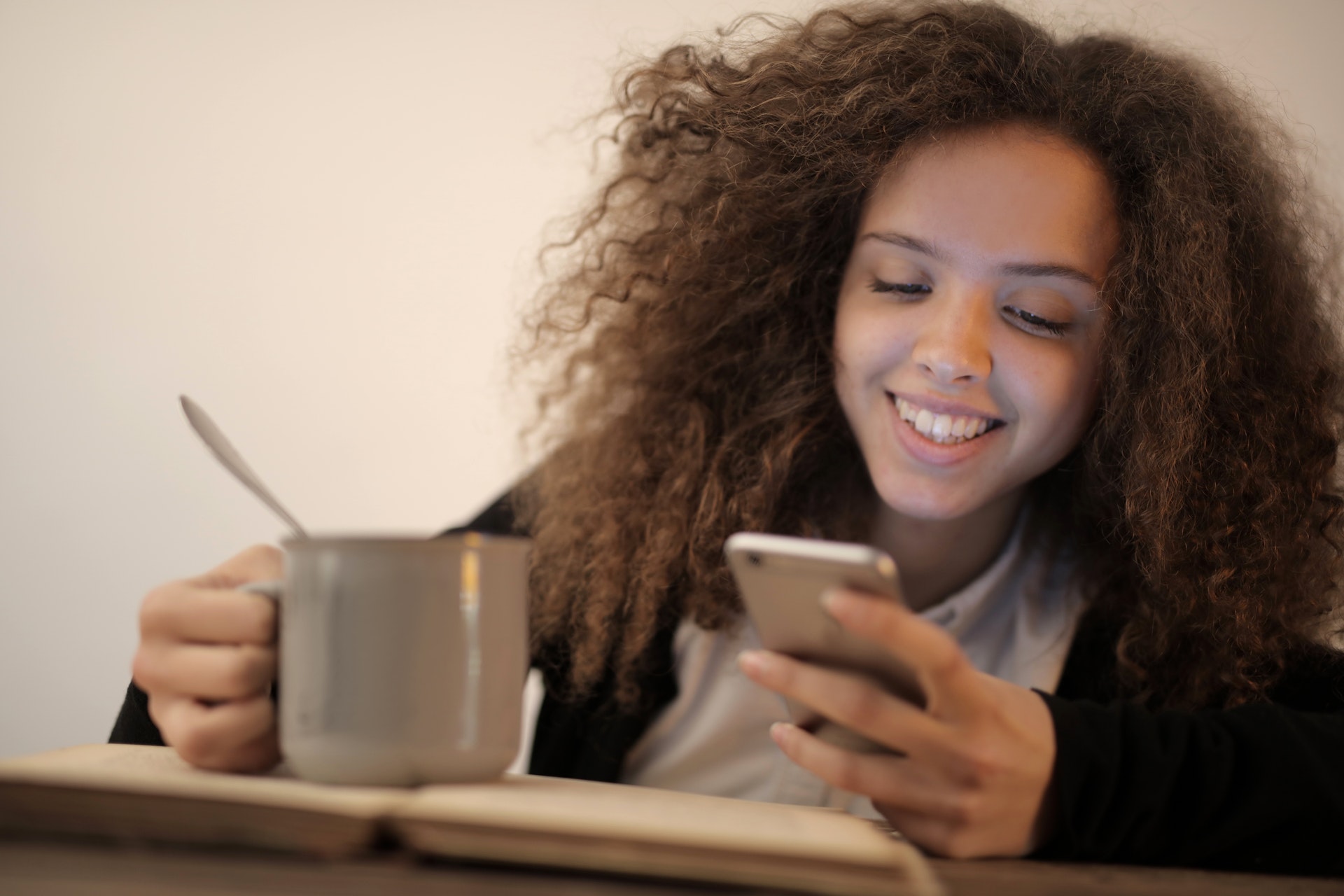 happy woman using mobile app with a cup on her hand