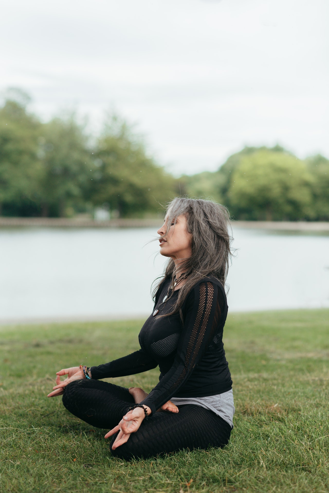 woman in grey hair wearing black and doing meditation