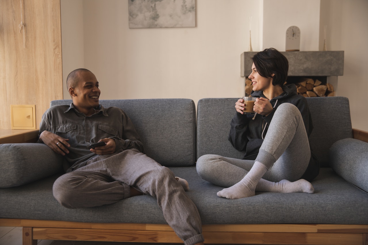 photo of an interracial couple sitting on sofa and laughing