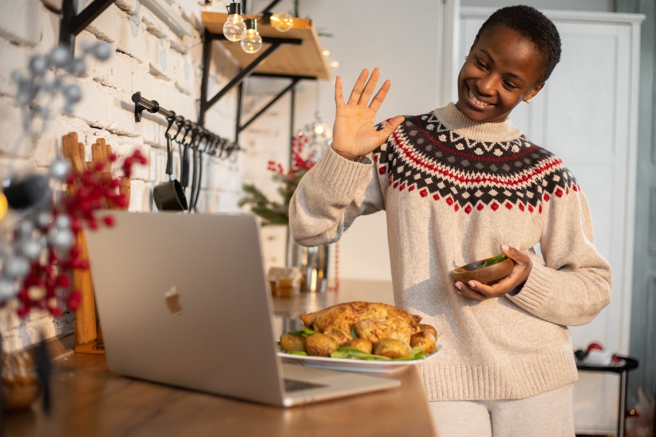 a black woman waving hand in front of a laptop