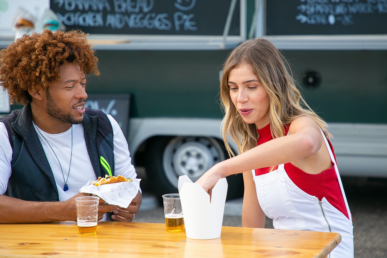 a man and a woman drinking beer and having fastfood