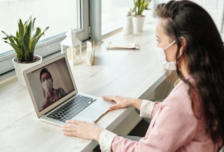 a young woman wearing mask and using laptop for video call