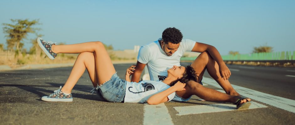 a woman laying on the road on a man's lap