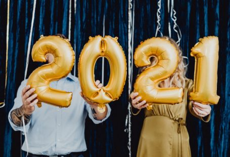 a man and a woman holding 2021 golden balloons