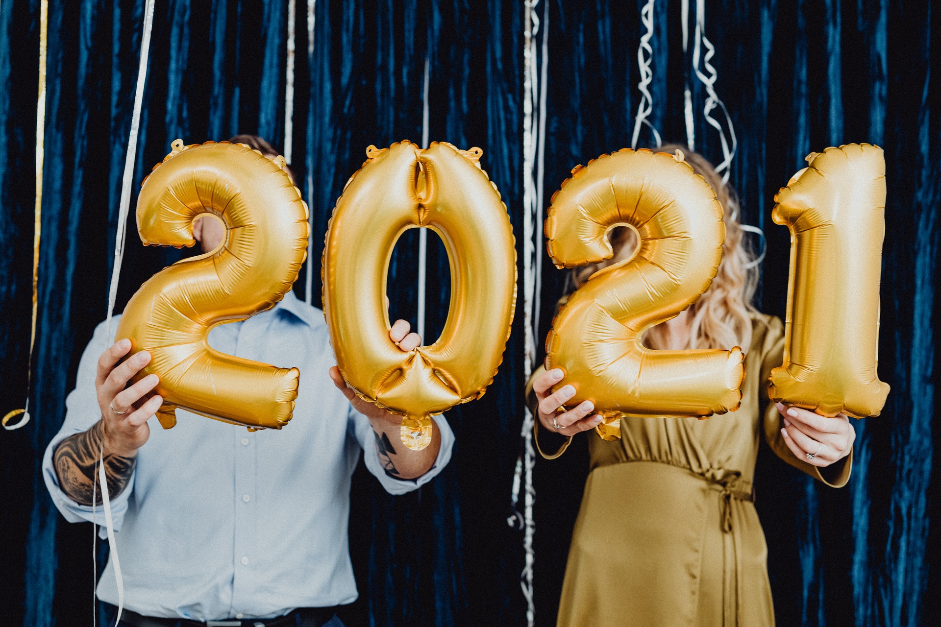 a man and a woman holding 2021 golden balloons