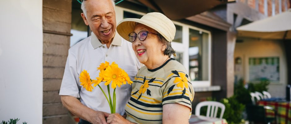 an elderly mature couple holding a bouquet of flower while holding hands
