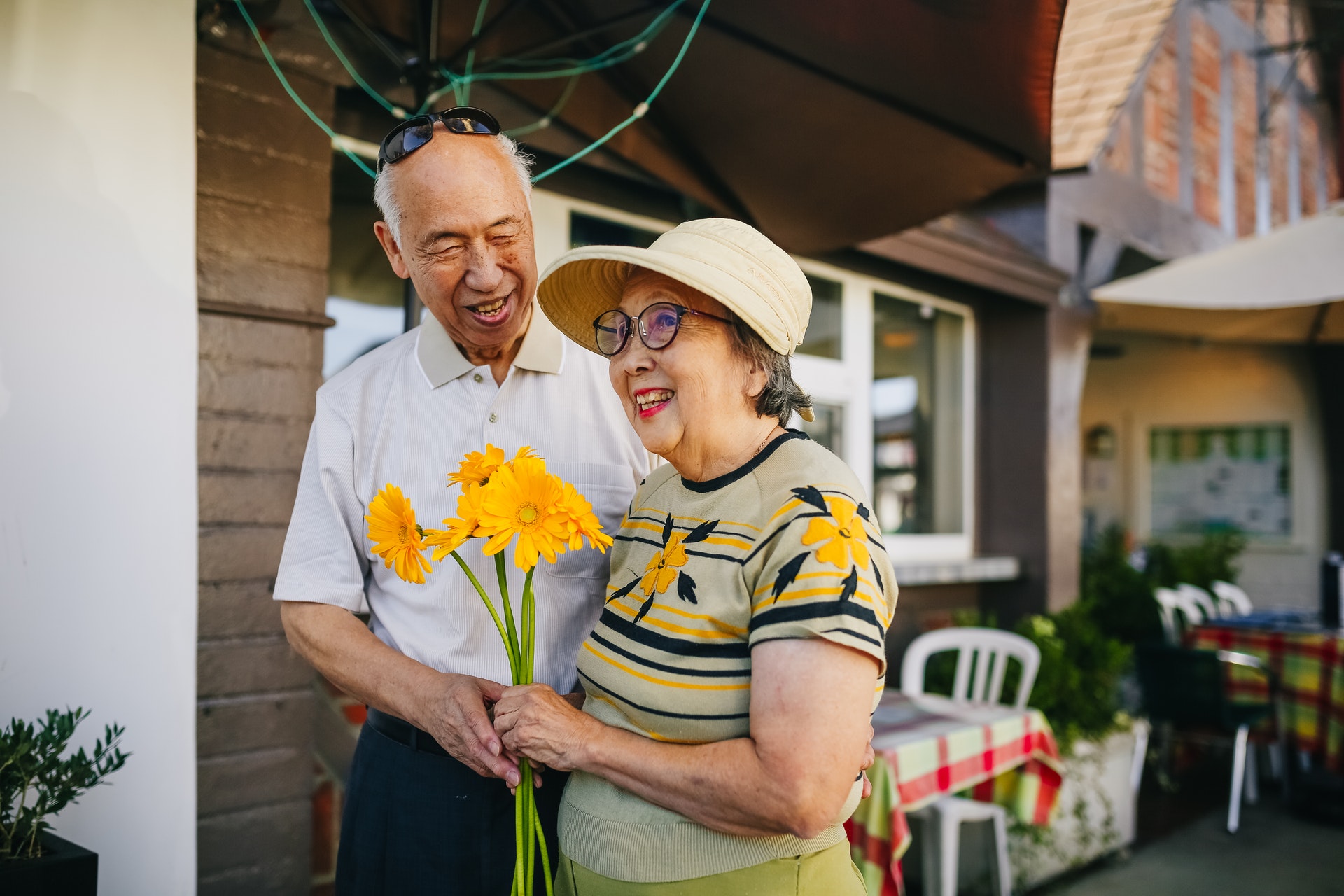 an elderly mature couple holding a bouquet of flower while holding hands