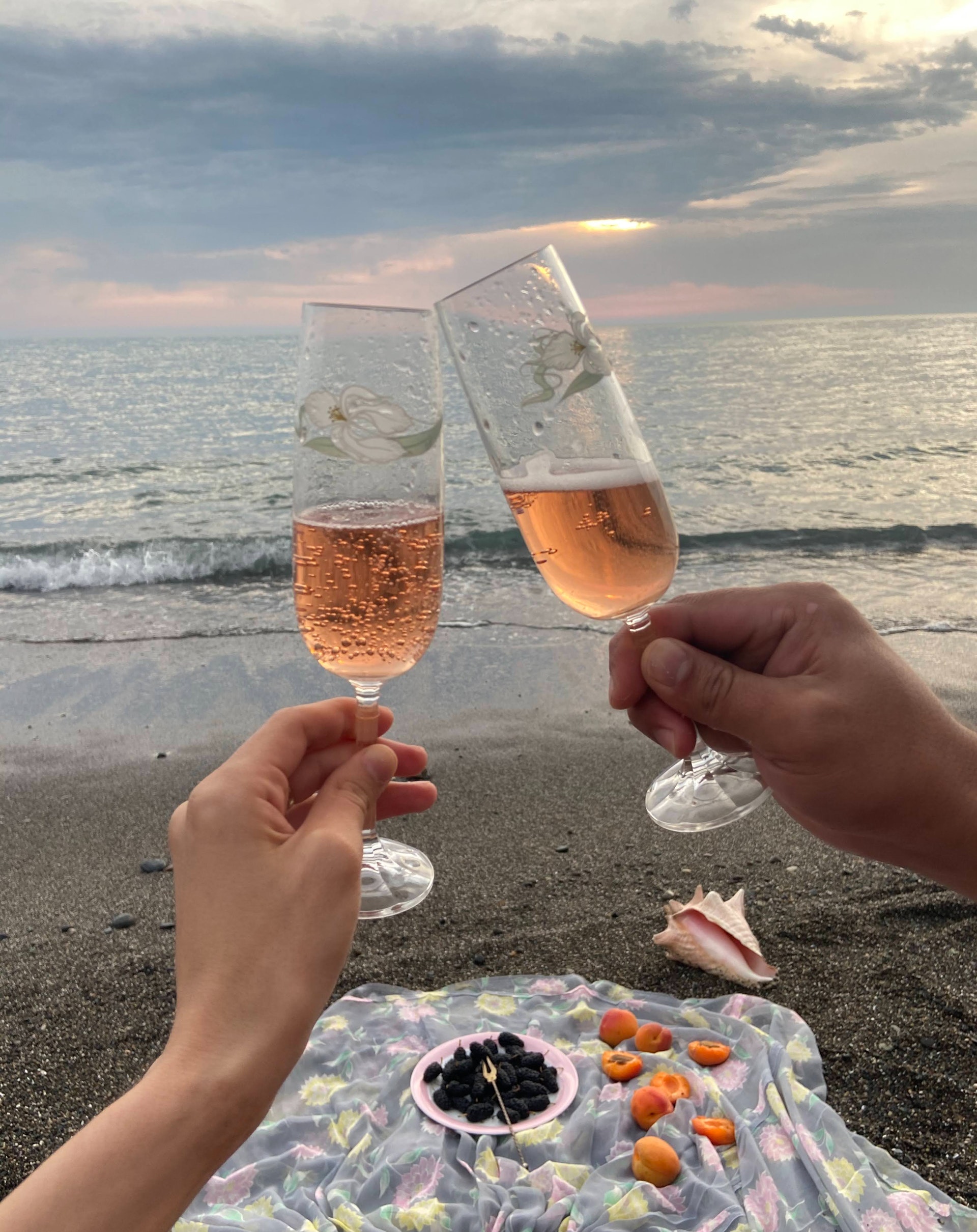 couple drinking glasses of champagne by seashore