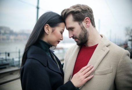 an asian woman in black holding a western man
