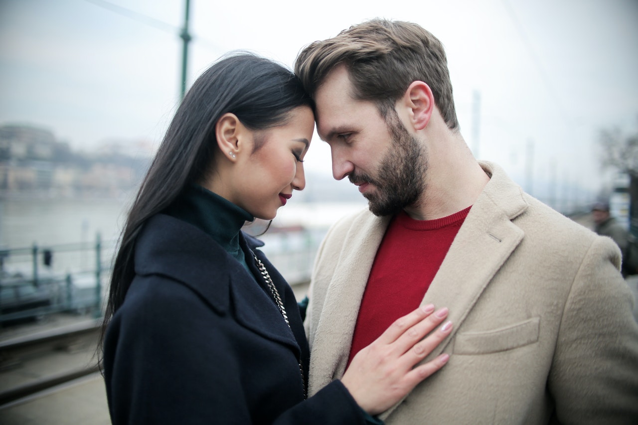 an asian woman in black holding a western man