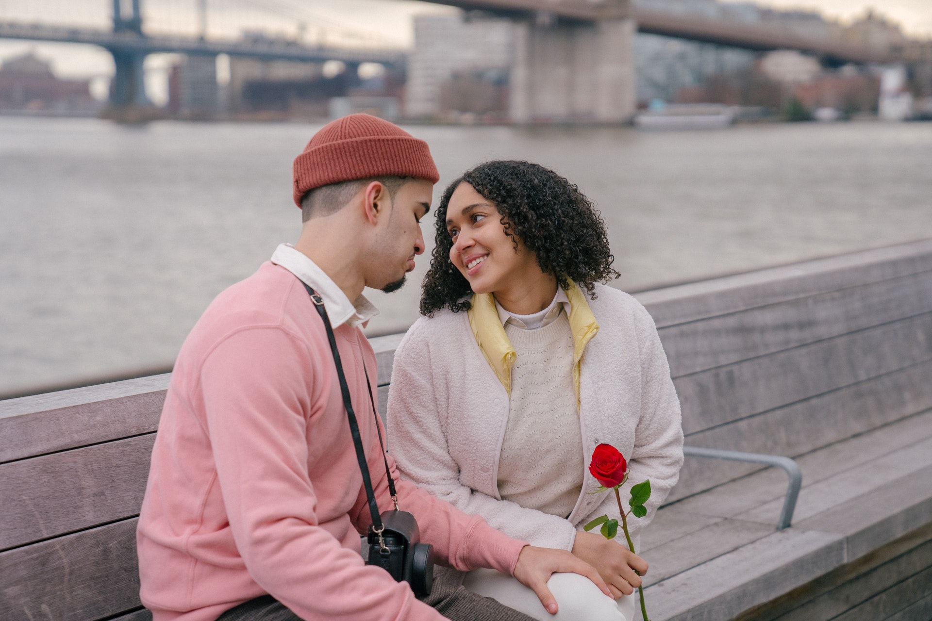 Hispanic couple with rose sitting on embankment