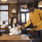 a black man giving flower to an asian woman on their first date at a coffee