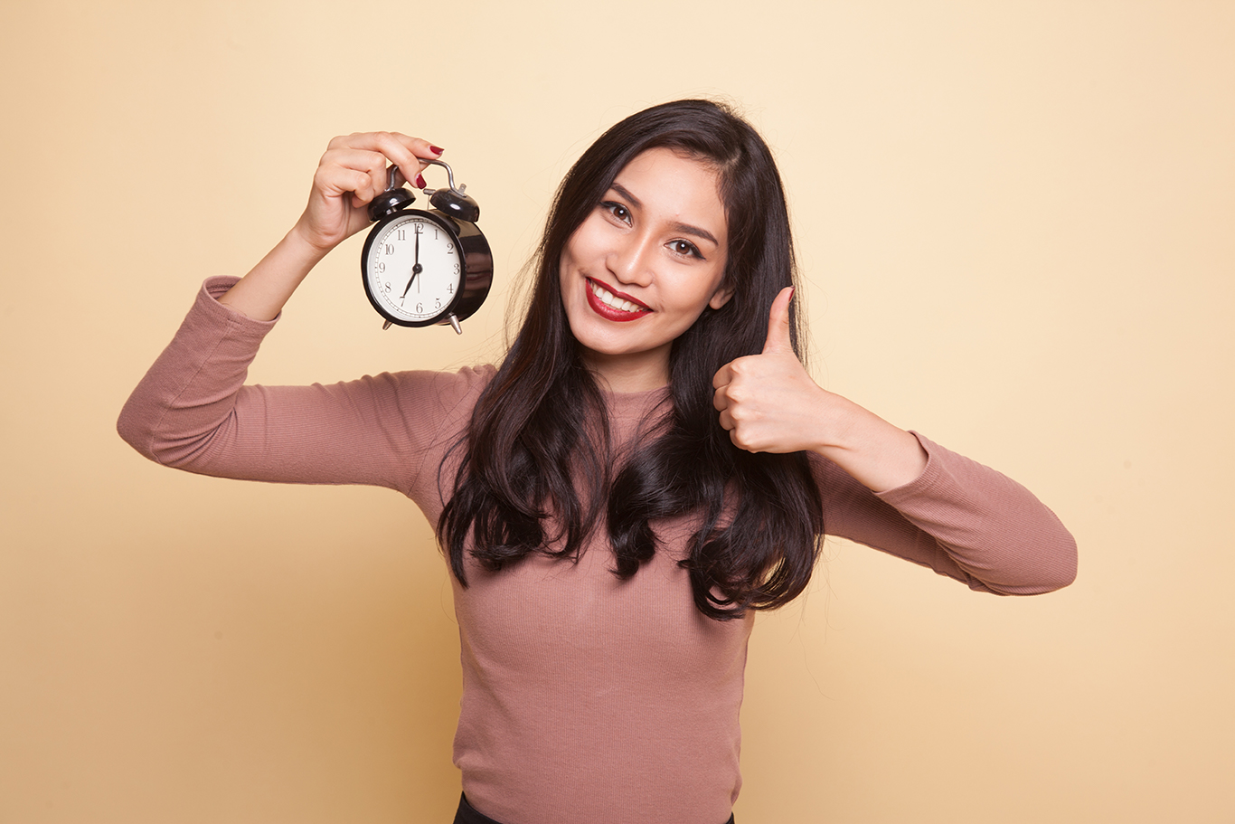 a latina holding a clock and thumb up