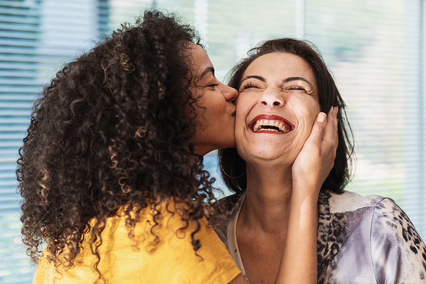 happy latin american family. curly-haired daughter kissing her mother