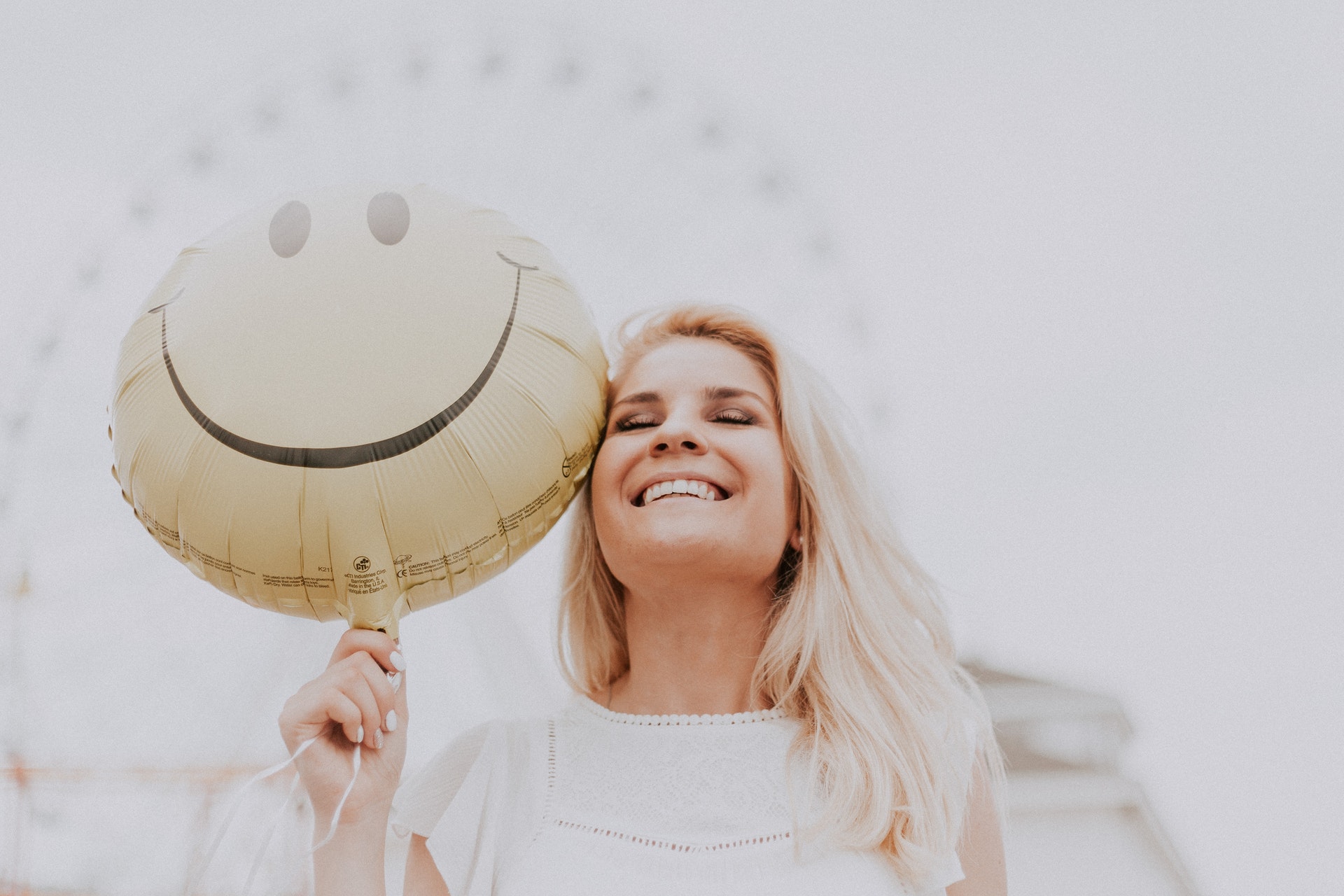 a smiling blonde woman holding a smile balloon