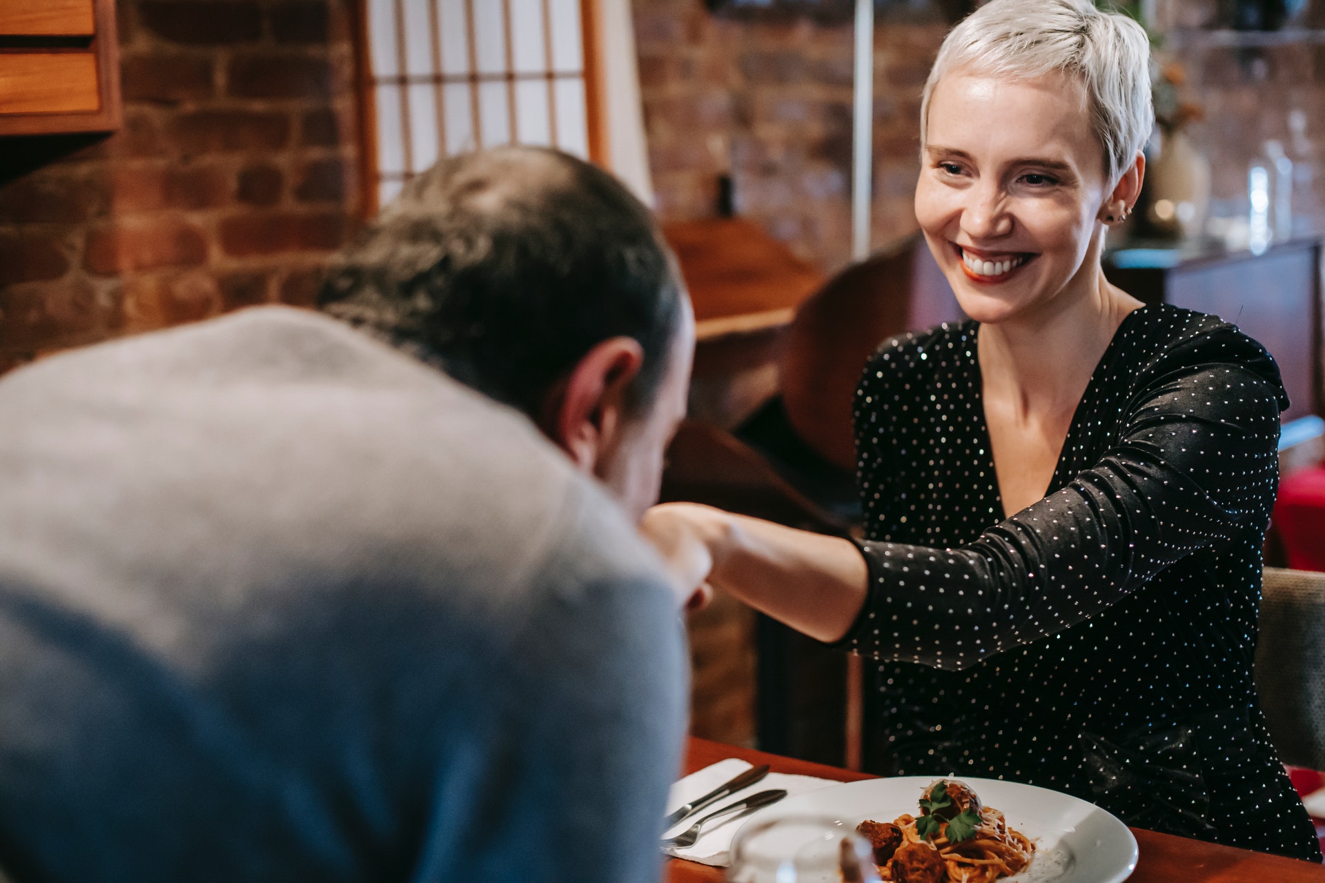 a couple having dinner in a restaurant and the man kissing the woman's hand