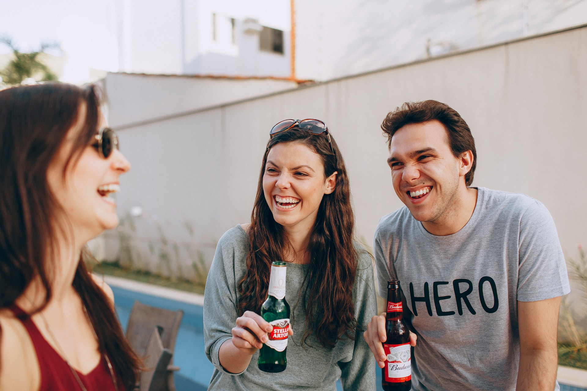 a couple and their friend holding beers and laughing