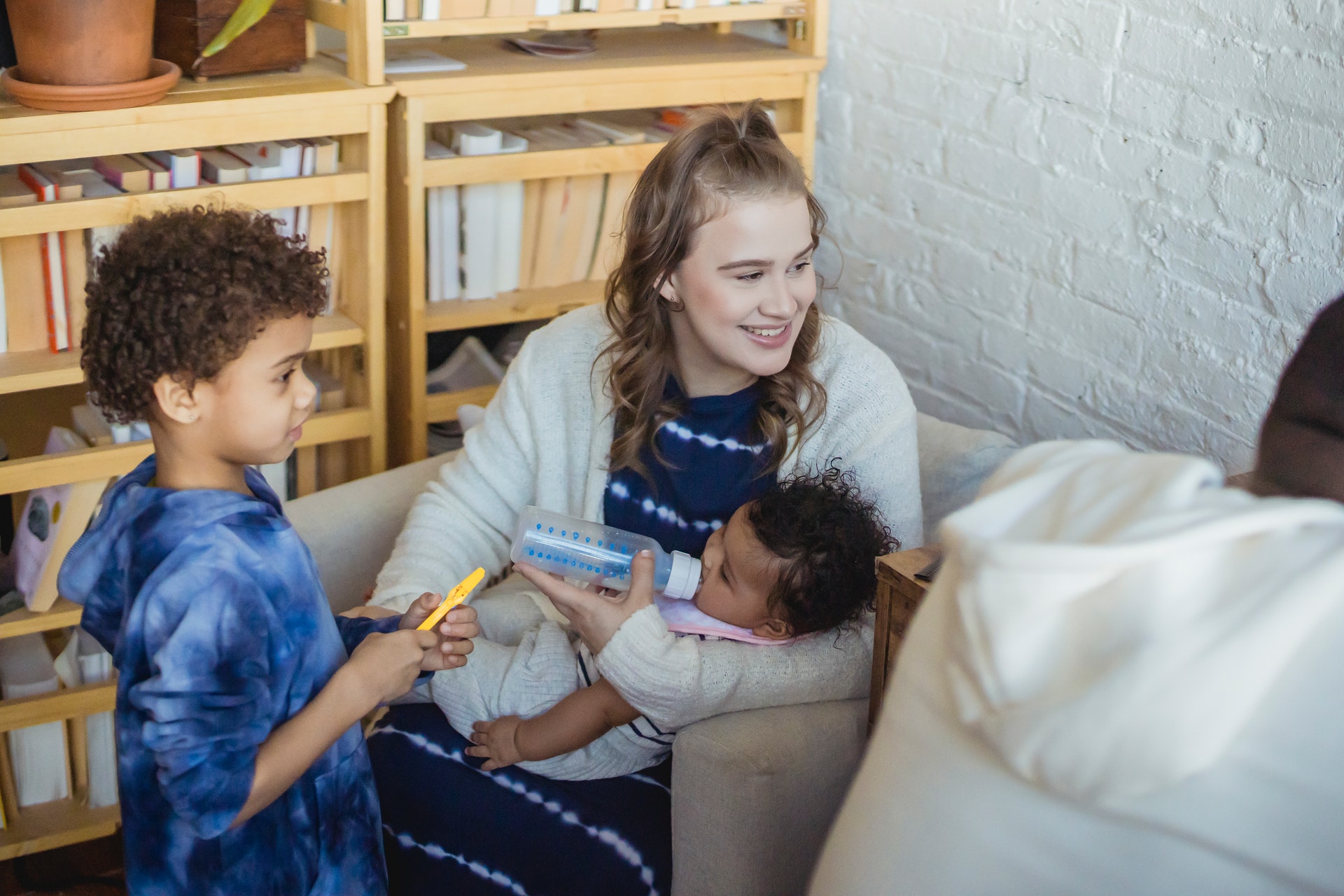 a cheerful diverse family with a mom is feeding her baby