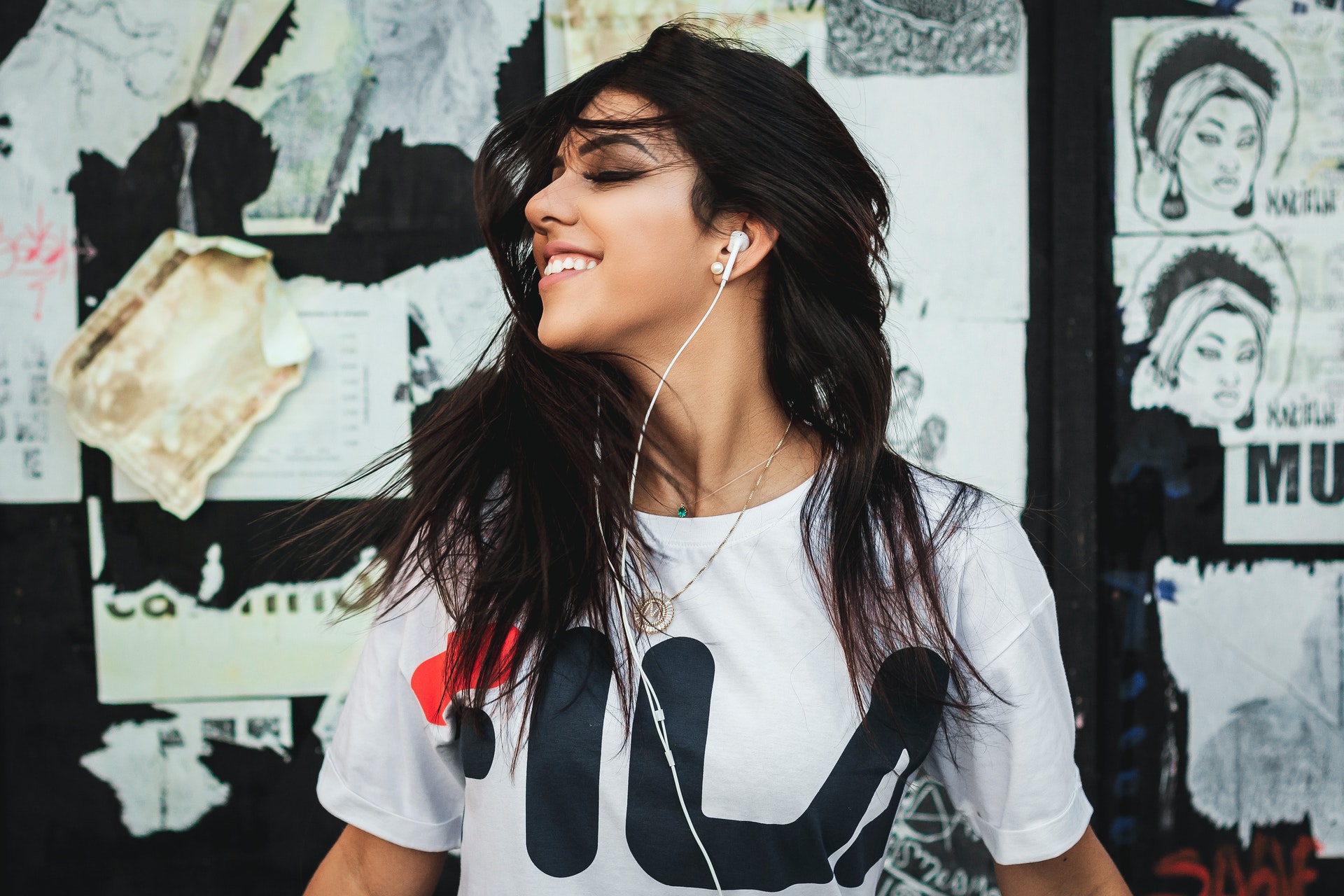 a Latina woman with earbuds on wearing a white shirt