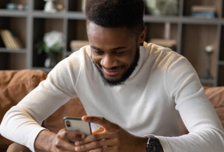 a smiling black man read cool online dating headline on sofa