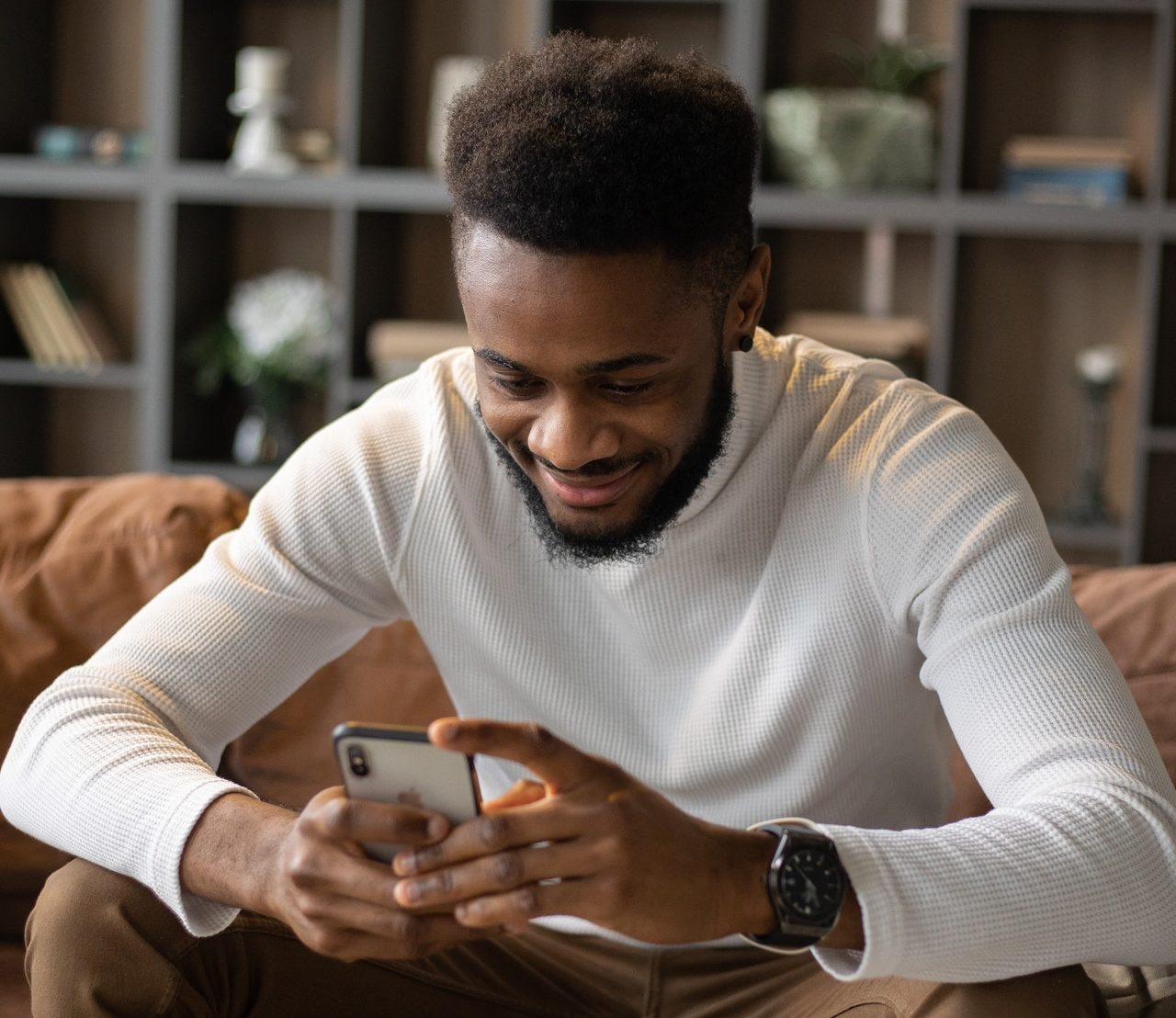 a smiling black man read a fantastic online dating title on the couch