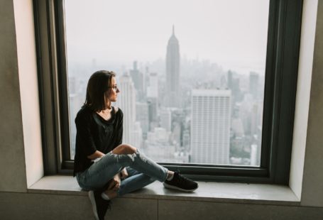 a single woman looking out of window with New York Empire States building view