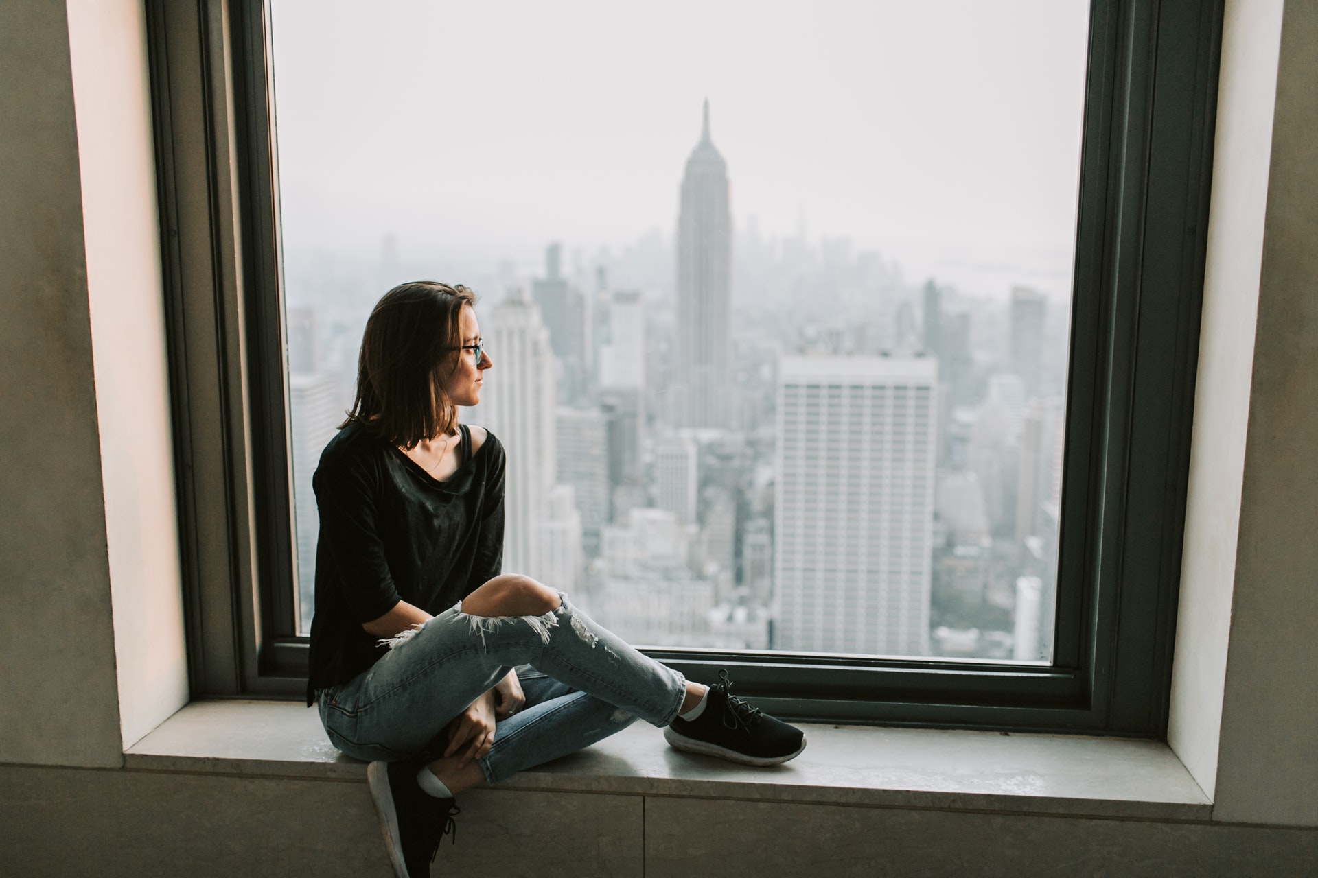 a single woman looking out of window with New York Empire States building view